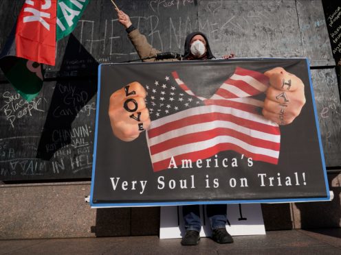 A protester holds a sign across the street from the Hennepin County Government Centre (Jim Mone/AP)