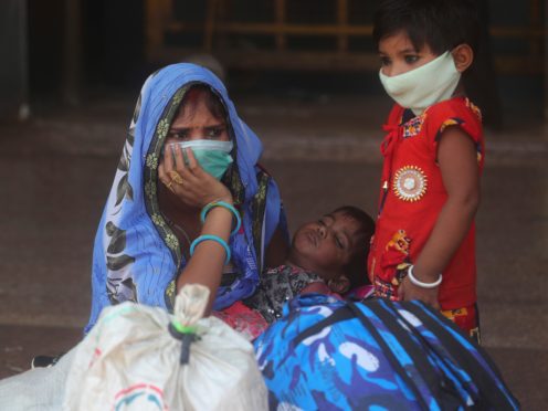 A woman and her children wait for a train at Lokmanya Tilak Terminus in Mumbai, India (Rafiq Maqbool/AP)