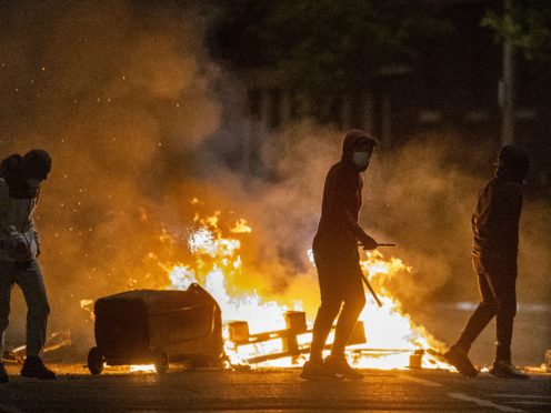 People stand next to a fire in a street in Belfast during further unrest. Picture date: Wednesday April 7, 2021.