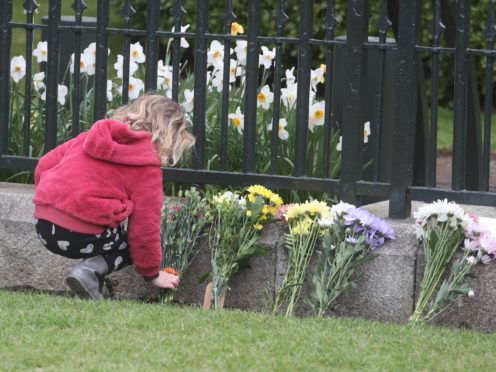 A girl leaves flowers outside Windsor Castle on Saturday (Steve Parsons/PA)