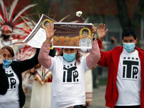 Demonstrators raise their hand as they attend a peace walk honouring the life of police shooting victim 13-year-old Adam Toledo (Shafkat Anowar/AP)
