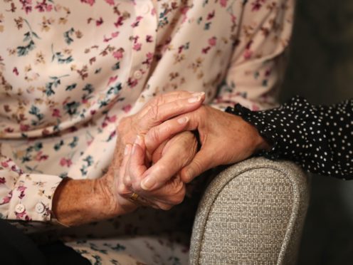A care home resident holds hands with her daughter (Andrew Matthews/PA)