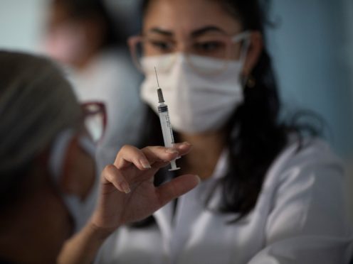 A healthcare worker prepares to inoculate a woman with a dose of the Sinovac COVID-19 vaccine, in Sao Joao de Meriti, Rio de Janeiro state, Brazil, Wednesday, April 28, 2021. (AP Photo/Silvia Izquierdo)