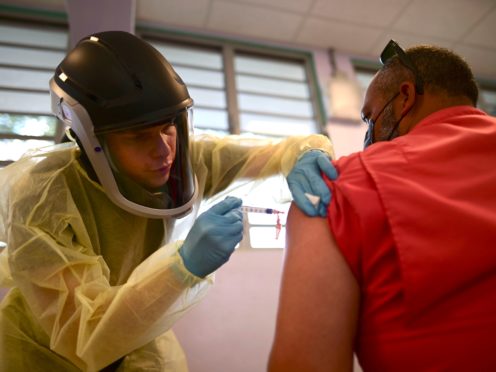 A healthcare worker injects a man with a dose of the Moderna Covid-19 vaccine in Puerto Rico (Carlos Giusti/AP)
