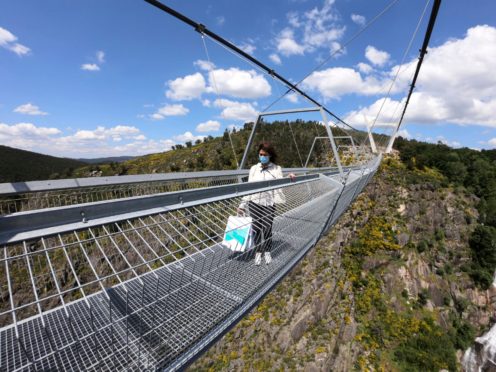 A woman walks across a narrow footbridge suspended across a river canyon, which claims to be the world’s longest pedestrian bridge, in Arouca, northern Portugal, Sunday, May 2, 2021. The Arouca Bridge inaugurated Sunday, offers a half-kilometer (almost 1,700-foot) walk across its span, some 175 meters (574 feet) above the River Paiva. (AP Photo/Sergio Azenha)