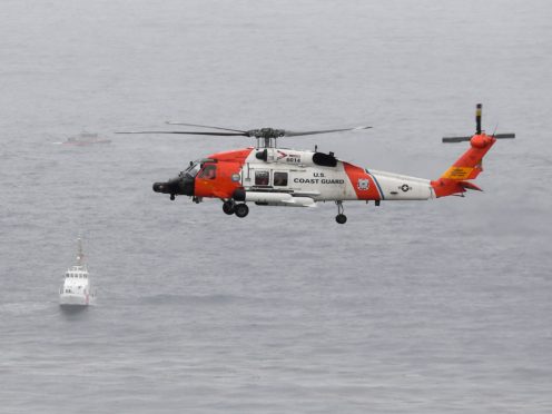 A US Coast Guard helicopter flies over boats searching the area where a boat capsized just off the San Diego coast (Denis Poroy/AP)