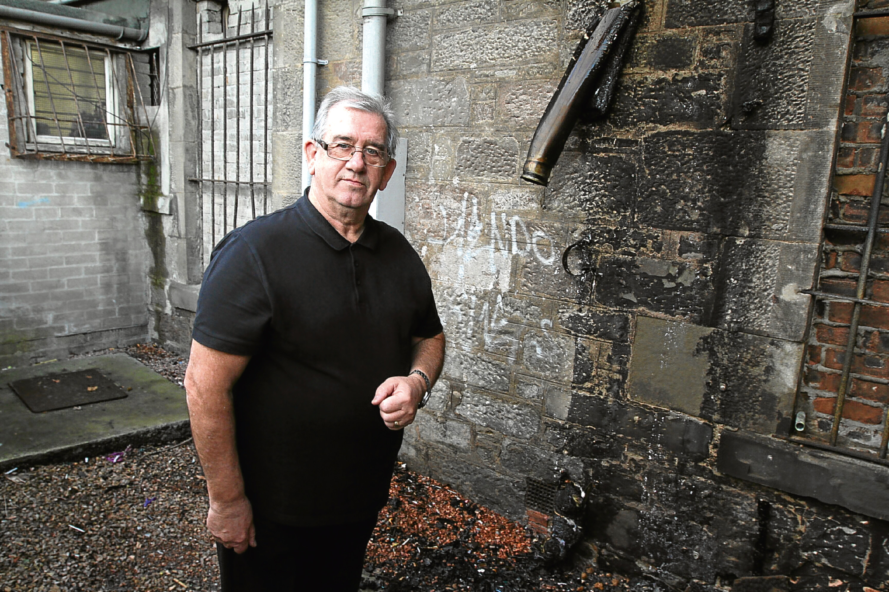 Jim Sturrock of Forte’s Cafe stands next to the sewage pipe which melted when a fire broke out.