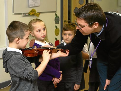Andy Thorn of the Big Noise Project sizes up some of the kids for violas at St Pius RC Primary School.