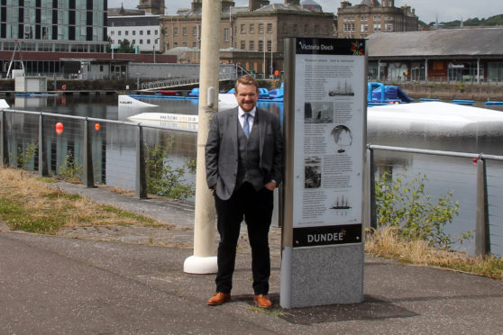 Councillor Alan Ross in City Quay with one of the signs that help make up the trail.