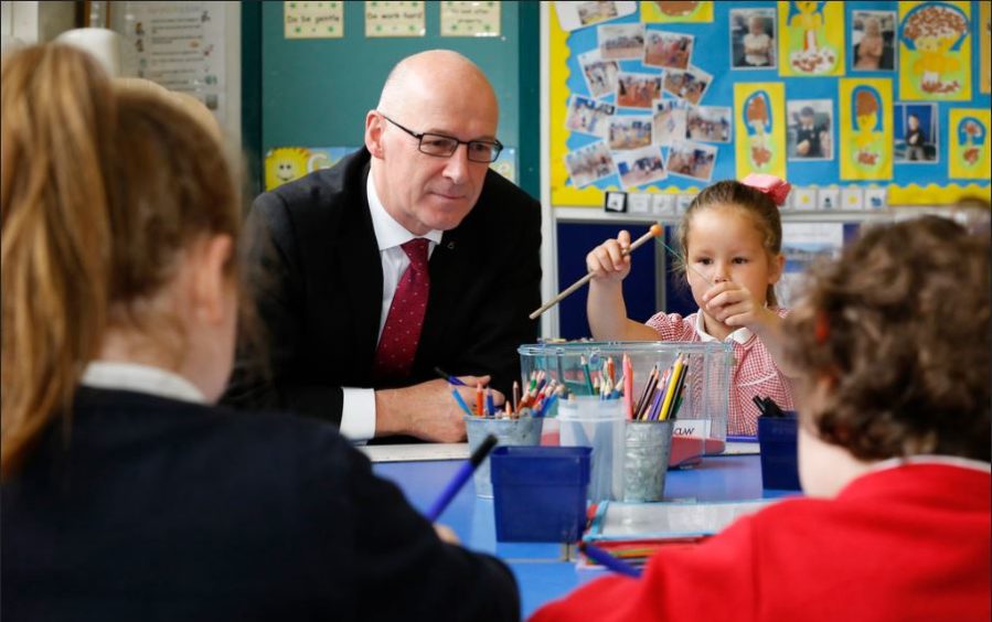 Education Secretary John Swinney helps pupils in school before lockdown.