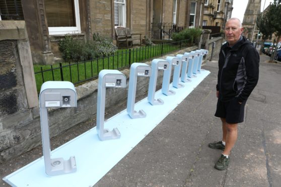 Dave Mulligan beside the electric bike charging station, installed by Dundee City Council, outside his flat in Blackness Avenue.