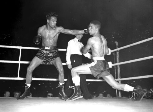 Sugar Ray Robinson (left) throwing a long left to the head of Randolph Turpin during their title bout at Earl's Court in London, in July 1951.