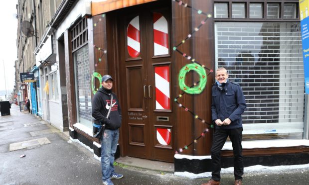 Sykes has transformed the exterior of a building in Stobswell into Santa's Post Office. Symon, left, is pictured with Colin Clement of the Stobswell Forum, whose idea it was to create the letter drop-off point.