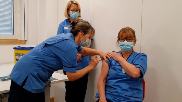 Staff nurse Linda Smyth receiving the first vaccine from Marion McLaggan with fellow COVID vaccinator Gill Allan. Supplied by NHS Tayside