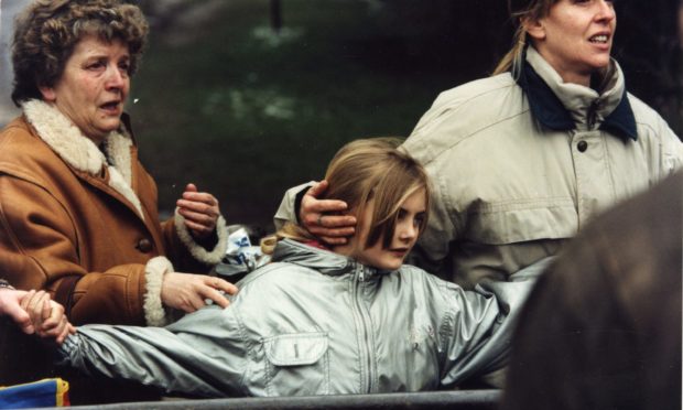 Two women hold hands with a young girl in Dunblane following the shootings.