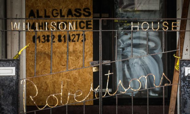 What was once a welcoming entrance to a family-run furniture emporium is now boarded up and vandalised.