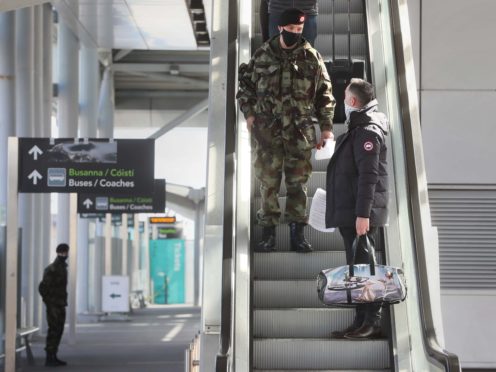 A passenger is escorted to a coach by a member of the Defence Forces after arriving at Dublin Airport (Brian Lawless/PA)