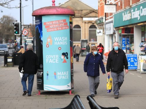 People wearing face masks walk past a coronavirus advice sign in Skegness, Lincolnshire (Mike Egerton/PA)
