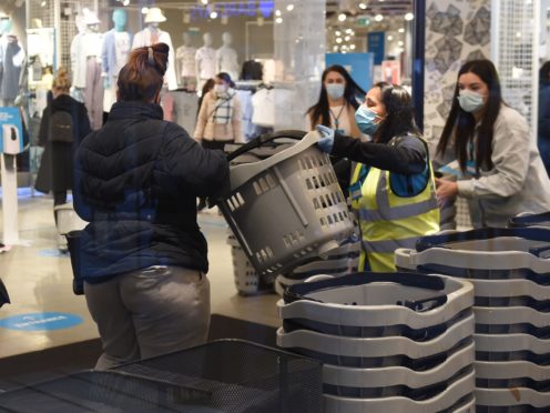 Early morning shoppers take a basket from a member of staff as they enter the Primark store in Birmingham (Jacob King/PA)