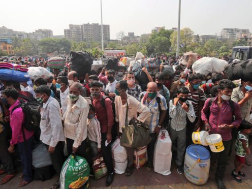 People wearing masks stand in queues to board trains at Lokmanya Tilak Terminus in Mumbai, India (Rafiq Maqbool/AP)