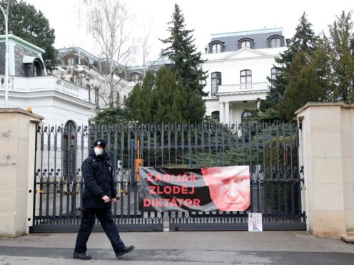 A policeman walks by a poster attached by protesters to a gate of the Russian embassy in Prague (Petr David Josek/AP)