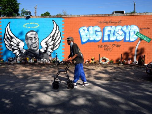 A man walks past a mural in the Houston neighbourhood where George Floyd grew up on Tuesday (David J Phillip/AP)