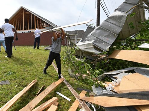 Derrick Pounds Jr. helps his father clean up debris around their house on Elvis Presley Drive in Tupelo, Miss., Monday, May 3, 2021. Multiple tornadoes were reported across the state on Sunday. (AP Photo/Thomas Graning)