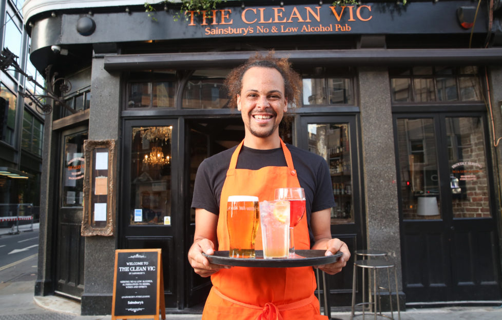 Man holding a tray of non-alcoholic drinks outside pub