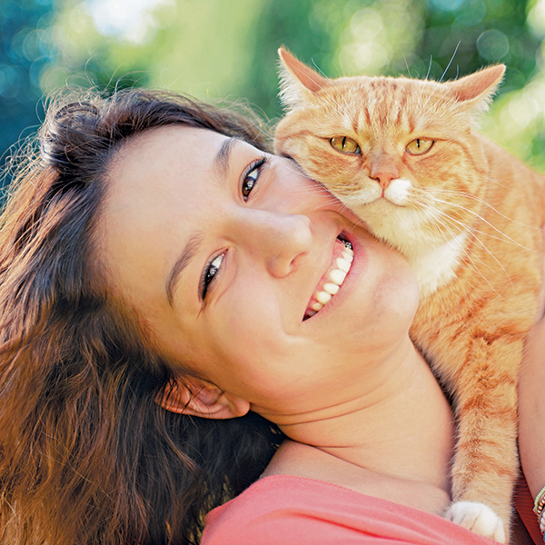 Smiling girl cuddling ginger cat