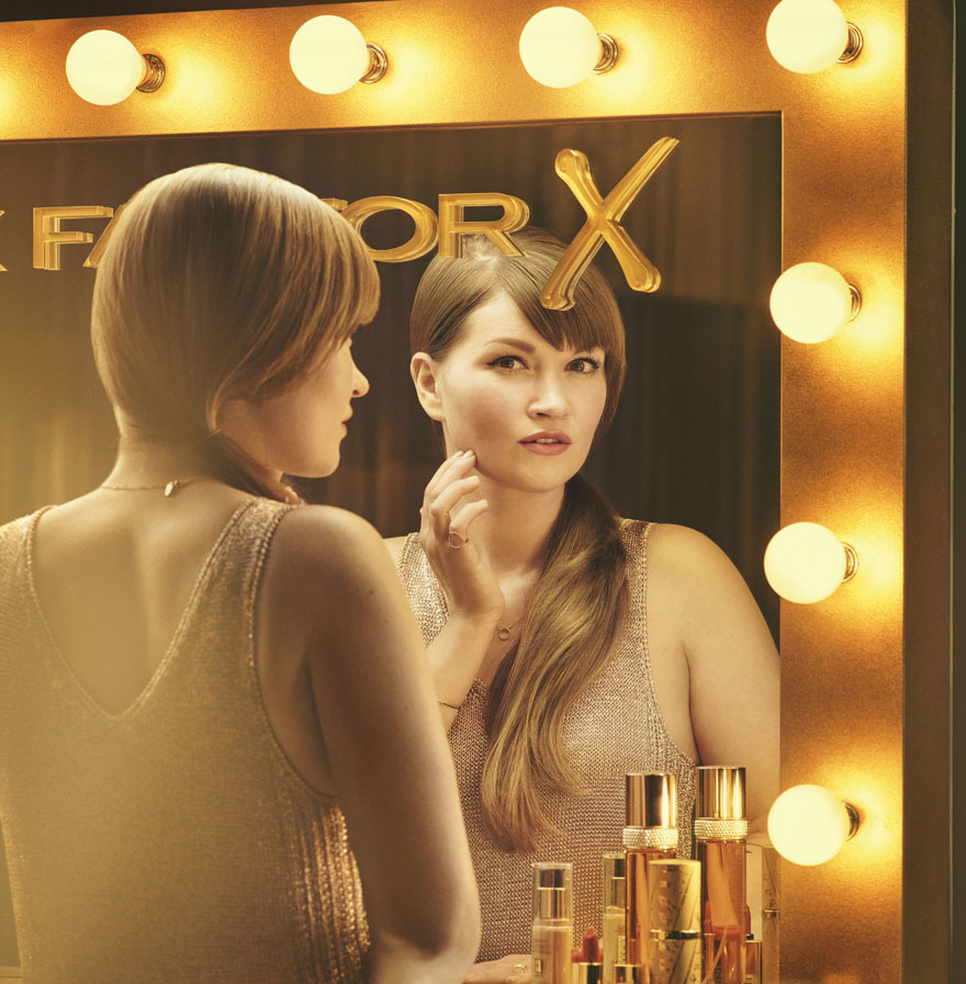 A lady applying make-up at an illuminated mirror