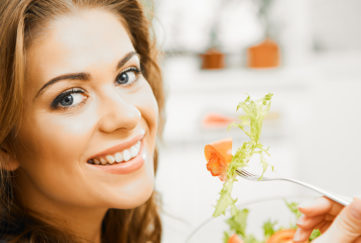A happy woman eating salad. A healthy diet is key in managing diabetes