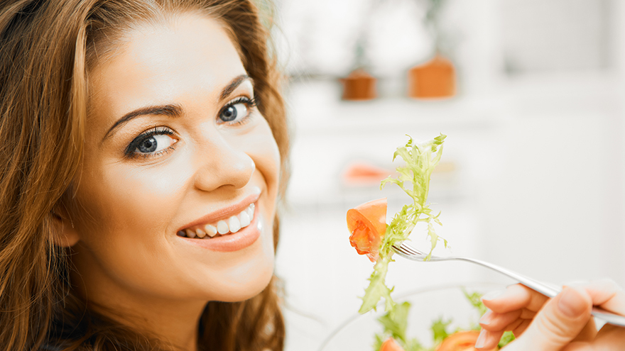 A happy woman eating salad. A healthy diet is key in managing diabetes
