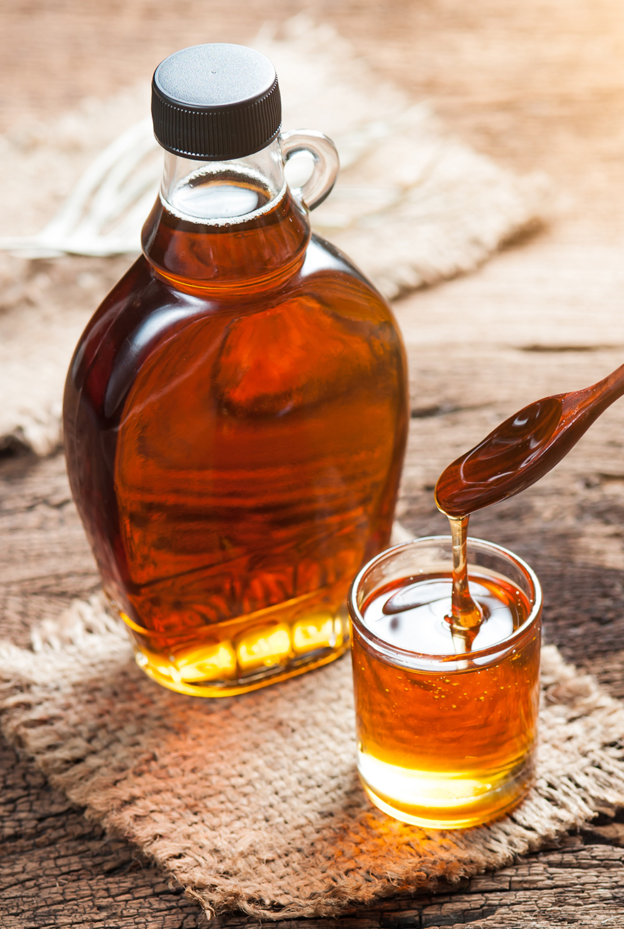 maple syrup, a natural sweetener, in a glass bottle on a wooden table