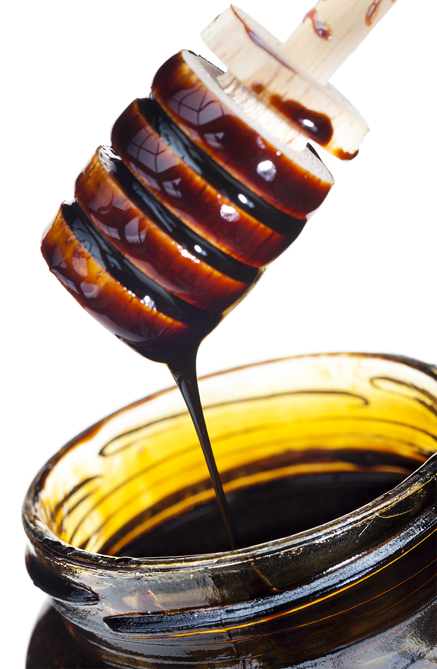 Blackstrap molasses, a sugar alternative, on a honey dipper
