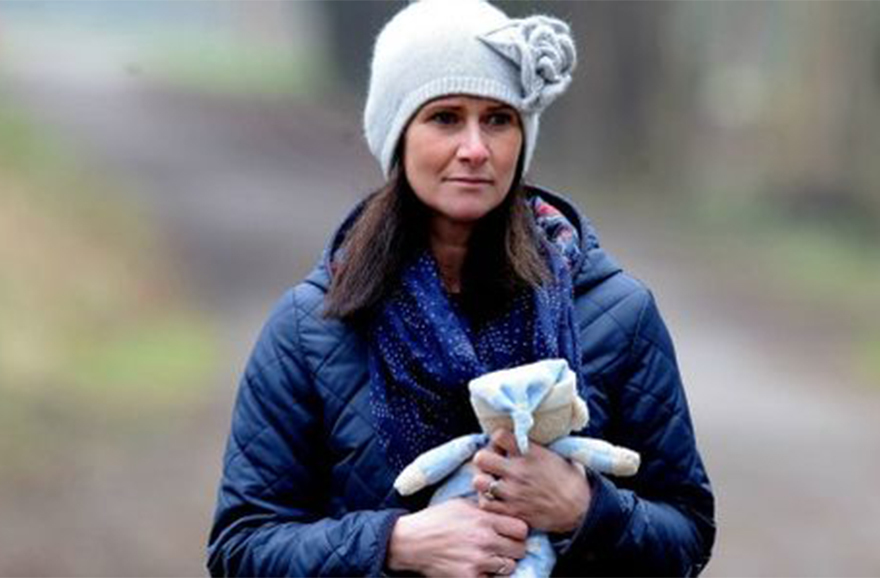 Rhian Burke, outdoors, looking pensive and holding a cuddly toy