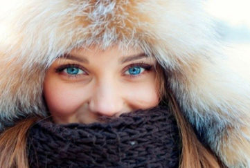 Smiling woman with bright blue eyes in furry hat and woollen scarf