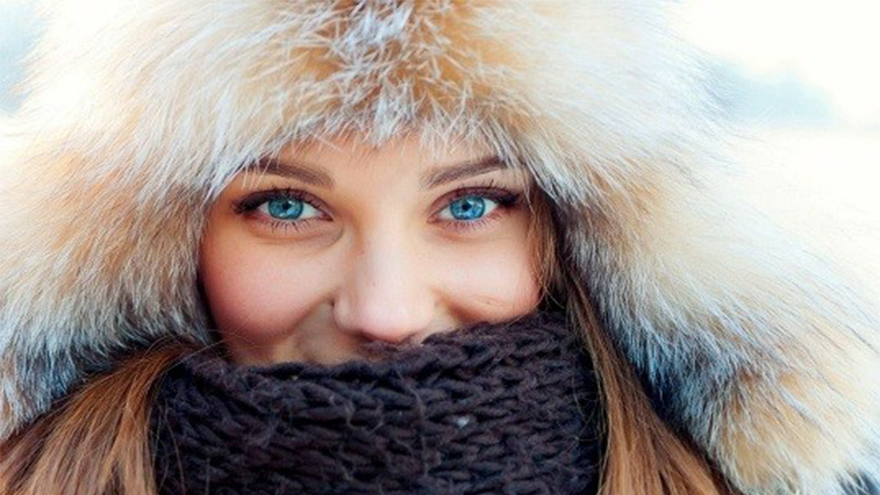 Smiling woman with bright blue eyes in furry hat and woollen scarf