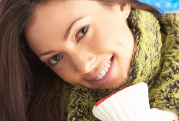 Smiling woman dressed warmly hugging hot water bottle
