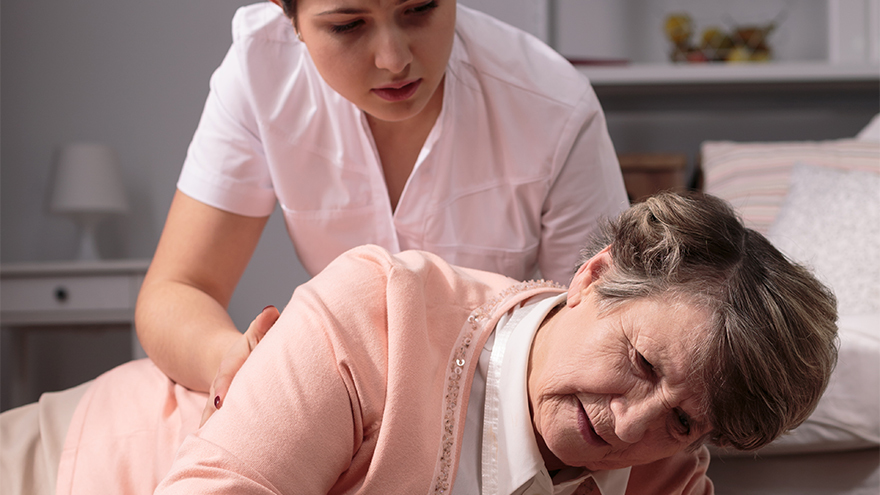 Helpful worried caregiver and senior woman on floor