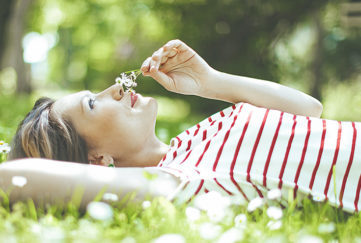 Lady lying on grass, smelling the flowers Pic: Istockphoto