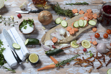 Wooden chopping board with onions, limes, carrots etc