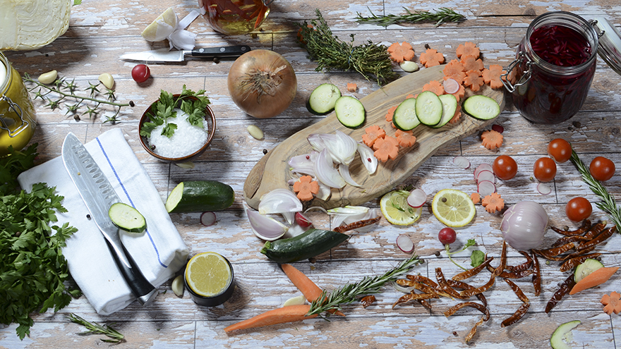 Wooden chopping board with onions, limes, carrots etc