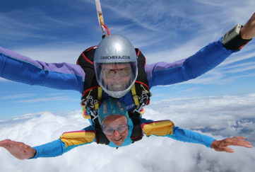 Alma Cater and skydiving partner smiling as they plunge through the sky