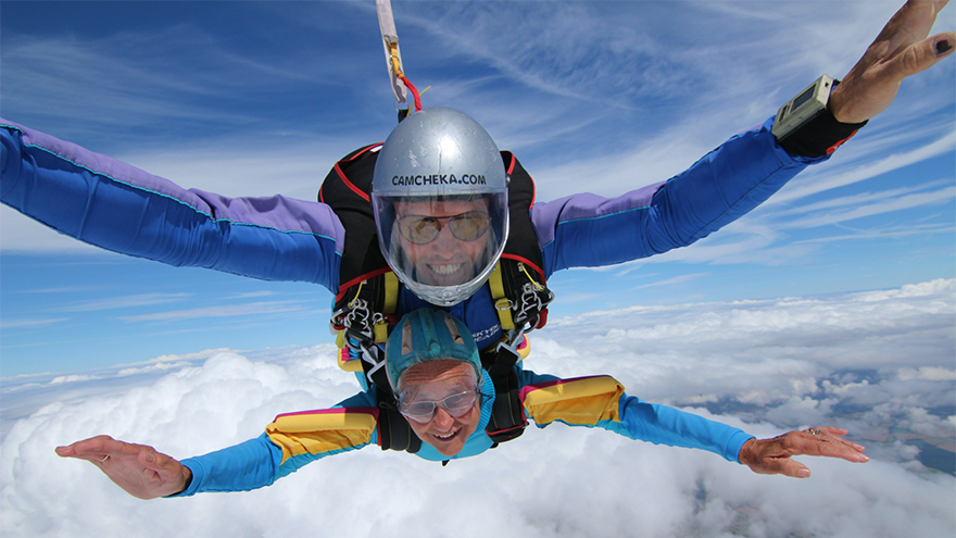 Alma Cater and skydiving partner smiling as they plunge through the sky