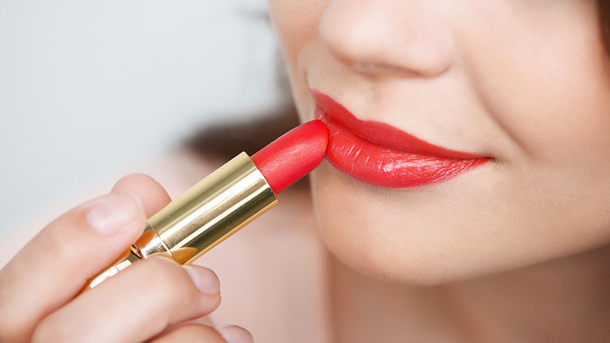 Lady applying red lipstick Pic: Istockphoto