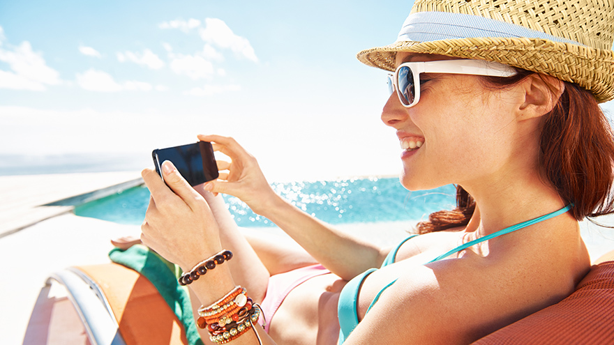 Lady on beach looking at mobile phone. Many phone cameras contain space tech Pic: Istockphoto