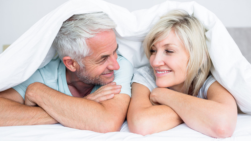 Mature couple in bed smiling at each other