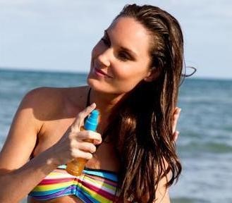 Woman spraying protecting spray on her hair