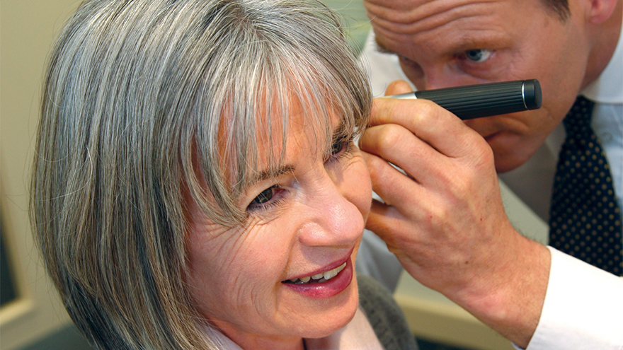Middle aged woman having her ear examined with a light