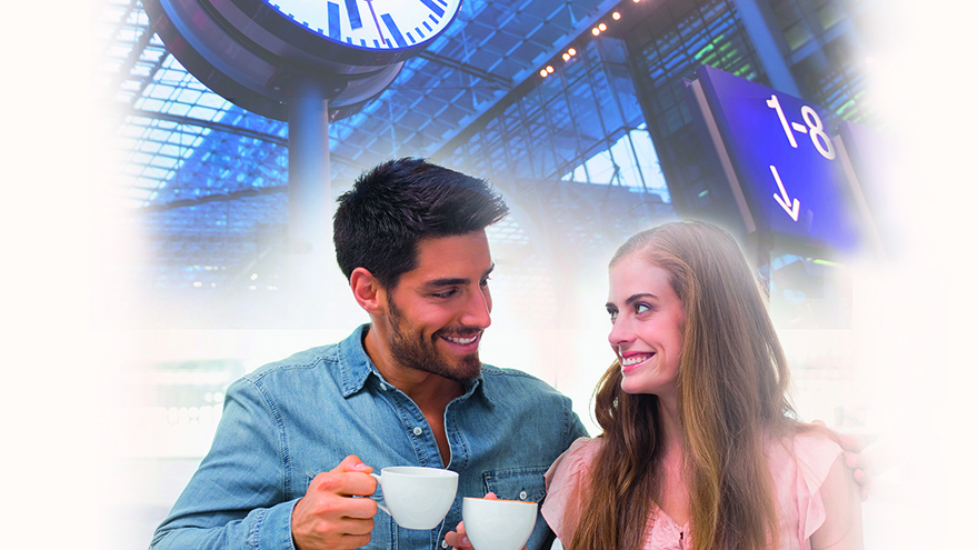 Smiling couple having coffee at train station